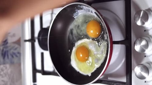Les
mains d'une jeune femme cassent un œuf et le versent sur la poêle en gros plan. Concept de petit-déjeuner