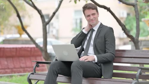 Man in Suit With Laptop Rubbing Neck