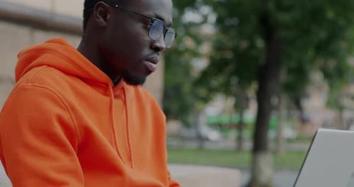 Man Works on Laptop in Urban Setting