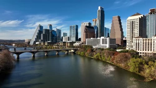 Aerial view low over the river, towards high-rise, sunny, fall day in Austin, USA