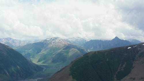 Stunning aerial panoramic view of continuous mountain range. Bright day, sky covered with large clou