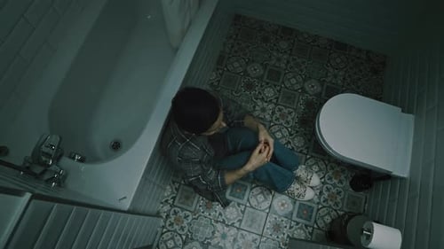 Top View of Depressed Woman Sitting on Floor in Bathroom