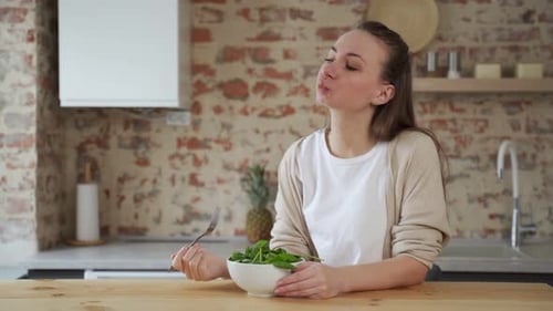 Woman Enjoys Fresh Spinach Salad in Kitchen