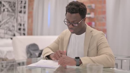 Man Reviews Documents at Glass Table in Office