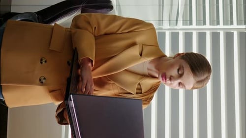 Vertical Screen Woman looking at laptop screen then smiling on camera in office