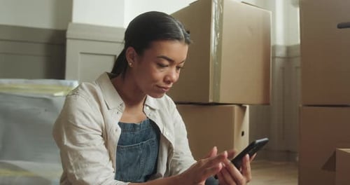Woman Using Phone with Moving Boxes