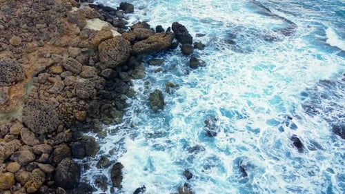 Sea Waves Washes the Rocky Shore Above Aerial Shot Flying Over Coastline Cliffside with Blue Pure