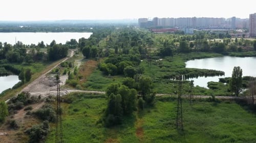 Blick von der Drohne, die über grüne, unbepflanzte Stadtwiese fliegt, umgeben von Teichen