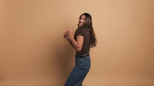 Woman Dancing Cheerfully Against a Plain Background