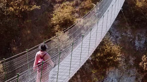 Une femme marche sur une passerelle suspendue en profitant des vues automnales