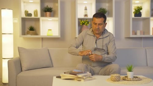 Man in Gray Sweats Taking Pills With Water