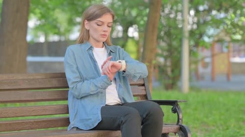 Young Woman Checking Smartwatch in Park