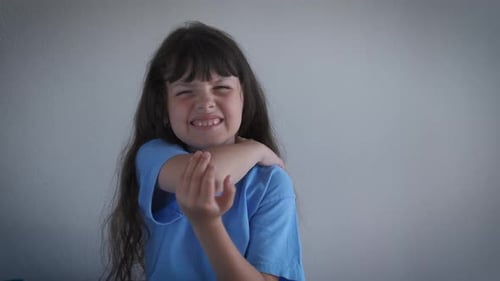 Girl Massaging Sore Elbow with Grimace