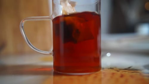Teebeutel in einem Glas Tee. Morgentee zubereiten. Schwarzteebeutel in einem Glasglas aufbrühen.
