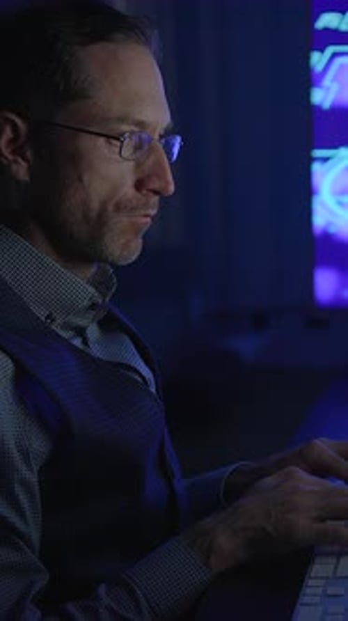 Un professionnel concentré et déterminé travaillant tard dans la soirée sur un appareil mobile dans des conditions de faible luminosité