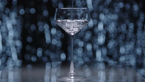 Clear Water Pouring Into a Standing Wine Glass in Light Gray Sparkling Background
