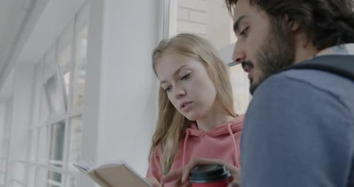 Man and Women University Students Reading Book and Talking Standing in Hallway Discussing Literature