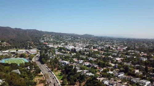 Aerial establishing shot of american highway in noble suburb district of Los Angeles in fall. Slow f