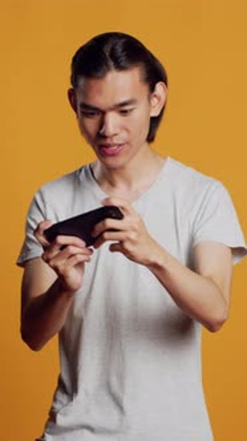 Vídeo vertical: modelo masculino feliz jogando Vídeo no smartphone