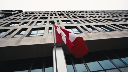 Canadian Flag Waving Against Modern Office Building