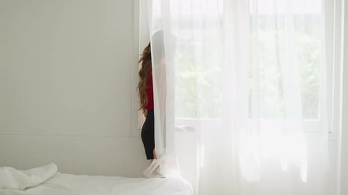 Woman standing near the window in bedroom