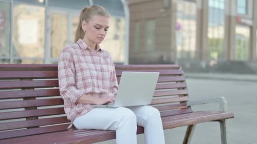 Woman Working on Laptop in Urban Park