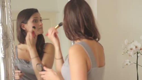 Close up rear view of woman reflected in mirror applying make up