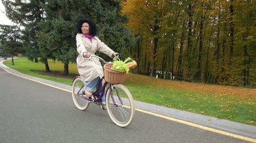 Happy Ride on a Bike in Autumn Park AfroAmerican Woman Cycling Along Road