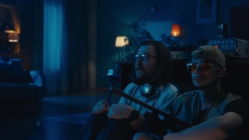 Two Friends Sit Together in a Dimly Lit Room