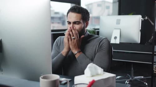 A Focused Man Engaged in Working on His Computer in a Modern Office Workspace Setting