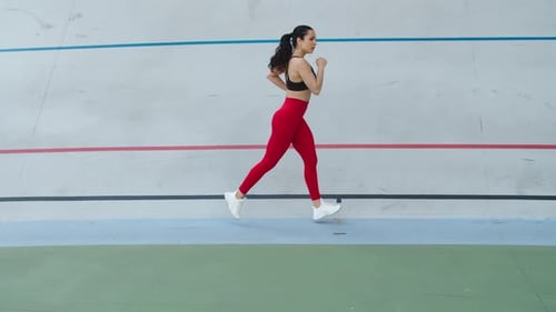 Fit young woman runner training cardio workout on athletics track at sport stadium