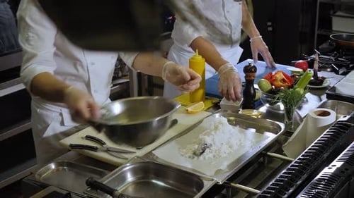Chefs Preparing Fish Dish in Commercial Kitchen