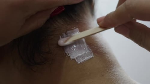 Macro Close Up Shot of a Wax Stick Applying Paste for Hair Removal on Neck