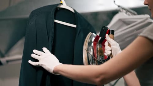 Close Up Professional Dry Cleaning Young Girl Irons a Black Sweater on Hanger with Steam