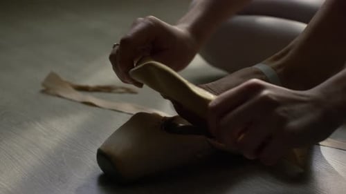 Dancer Putting on Pointe Shoe With Taped Toes