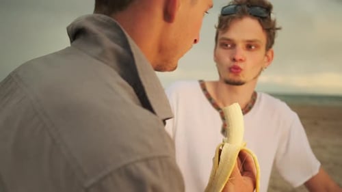 Молодой геи Флирт молодой гей-пары на романтическом свидании на пляже, два парня едят банан и флиртуют , Стоковые видеоматериалы Включая: флиртует и заигрывание - Envato
