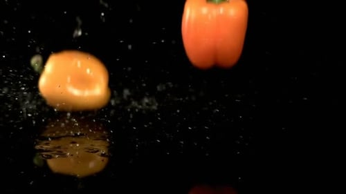 Colorful bell peppers falling and splashing on surface