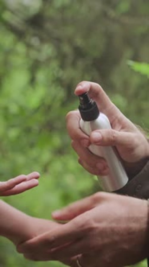 Spraying Insect Repellent on Child Arm in Forest