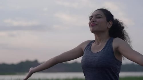 Vista de perto de uma mulher do sul da Ásia estendendo os braços graciosamente durante uma sessão calma de ioga