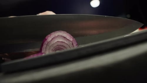 Knife Slicing Red Onion on Cutting Board