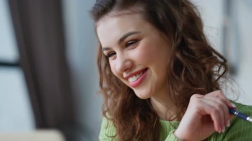 Woman Smiling while Working on a Laptop