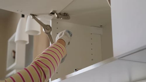 Woman Building Kitchen Cabinet with Screwdriver