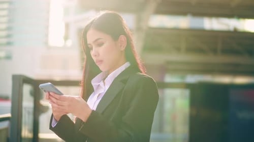 Woman Using Phone on Sunny Day in the City
