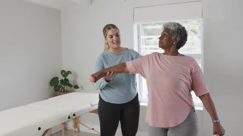 Woman Helping Senior with Arm Stretching Exercise