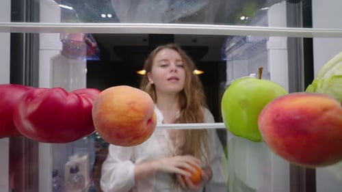 View From Inside Fridge Woman Opens Side By Side Fridge Doors Takes Fruits and Vegetables Closes It