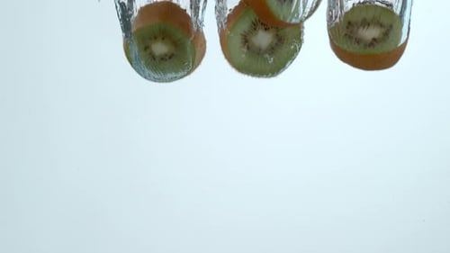 Kiwi Fruit Slices Falling Into Water in Slow Motion
