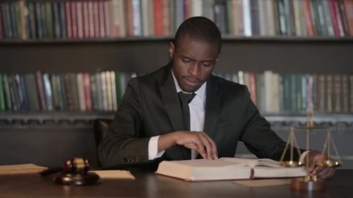 African Male Lawyer Reading Law Book in Office