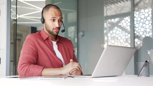 Businessman in wireless headset talking on a video call conference using laptop in office. Manager