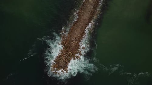 Breakwater Jetty Protecting Coastline from Ocean Waves - Aerial Drone Top Down Rotating View