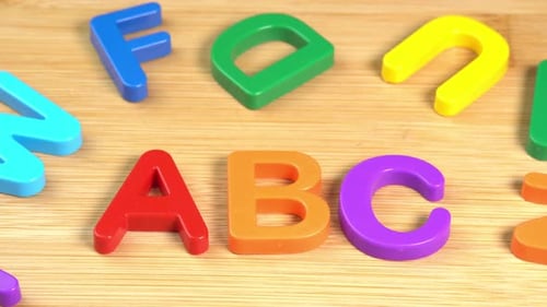 Colorful ABC Alphabet letters rotate on a wooden background. The concept of learning, school